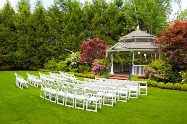 Outdoor wedding venue with white chairs and a big gazebo